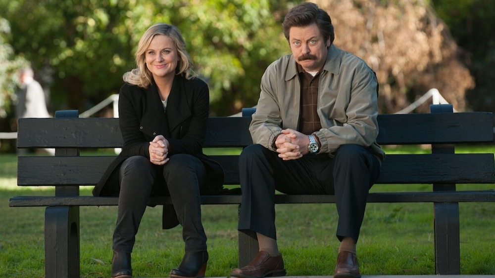 Leslie Knope and Ron Swanson sitting on a bench