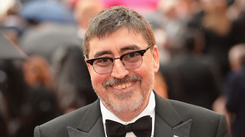 Alfred Molina smiling and wearing glasses