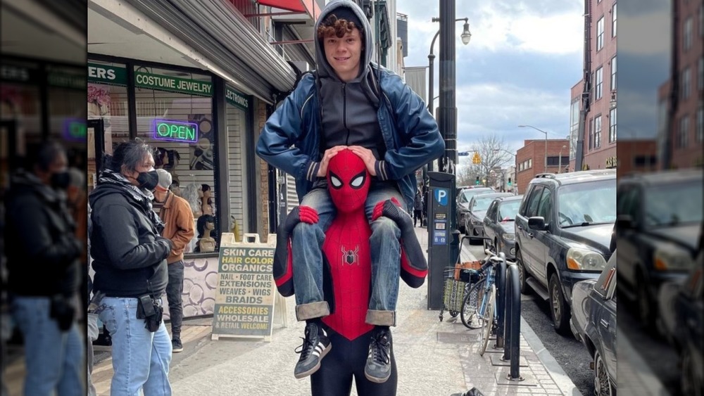 Tom Holland in Spider-Man costume holding his brother