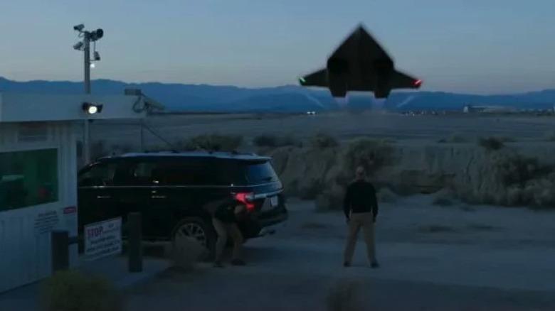 Man stands outside while jet flies over him