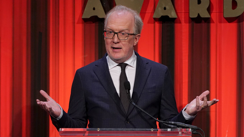 Tracy Letts on stage in front of red curtain