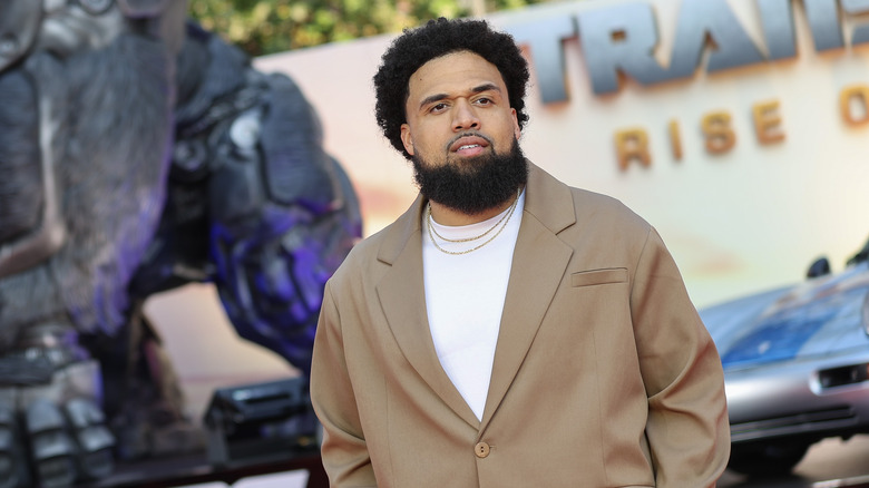 Steven Caple Jr. standing in front of a Transformers: Rise of the Beasts display