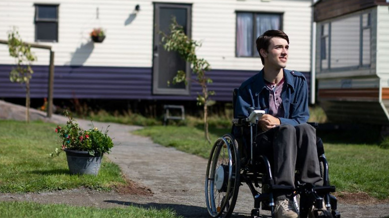 Isaac sits in wheelchair by trailer