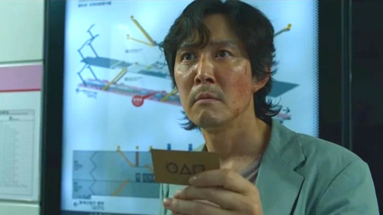 Gi-hun holding a Squid Game card