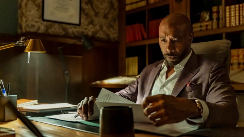 Dr. John Watson reading documents at his desk