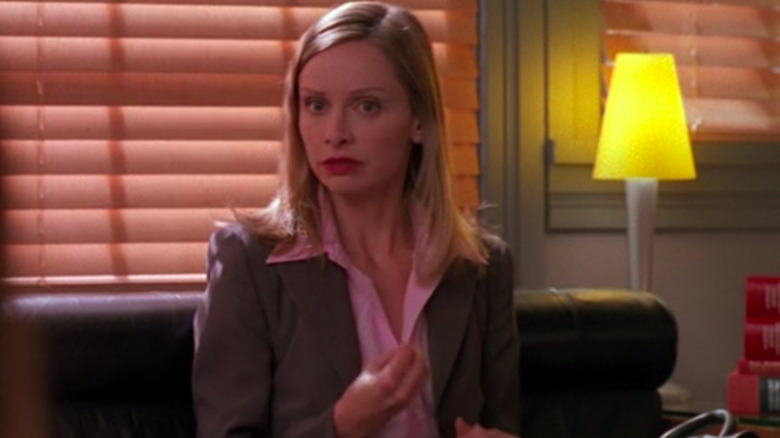 Ally McBeal sits on a couch