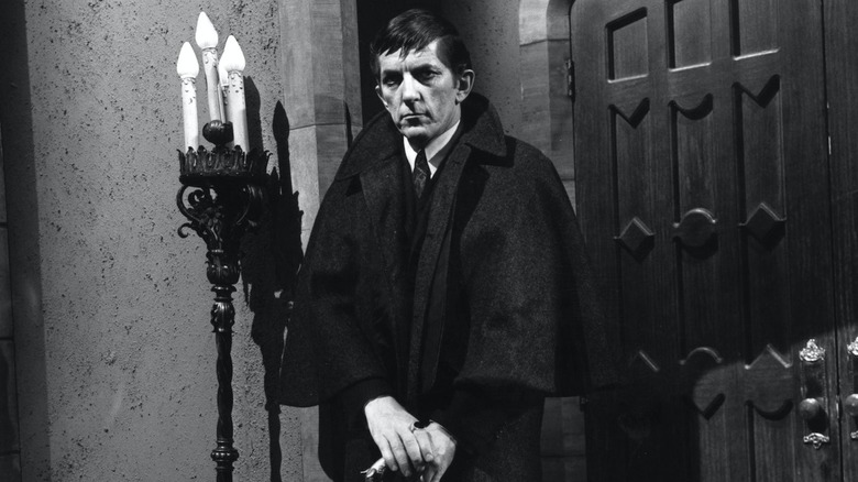 Barnabas stands in front of a door