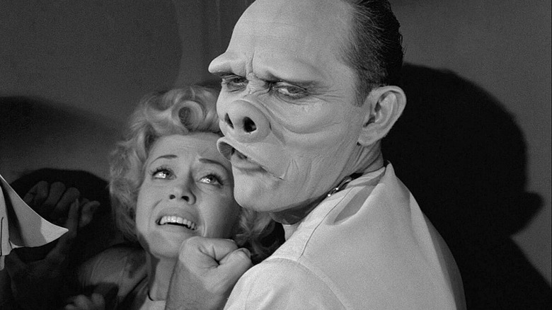 A pig-faced man holds a woman