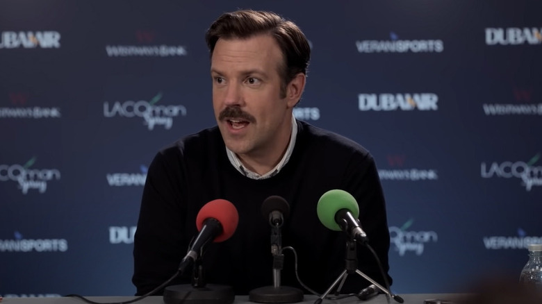 Ted Lasso speaking into microphones