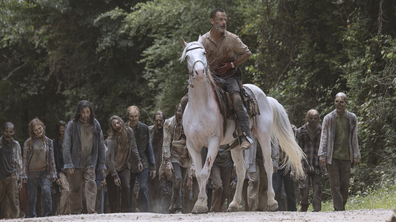 Rick rides a horse ahead of a zombie horde