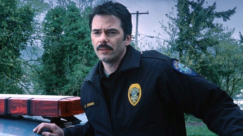 Charlie Swan leaning on police car