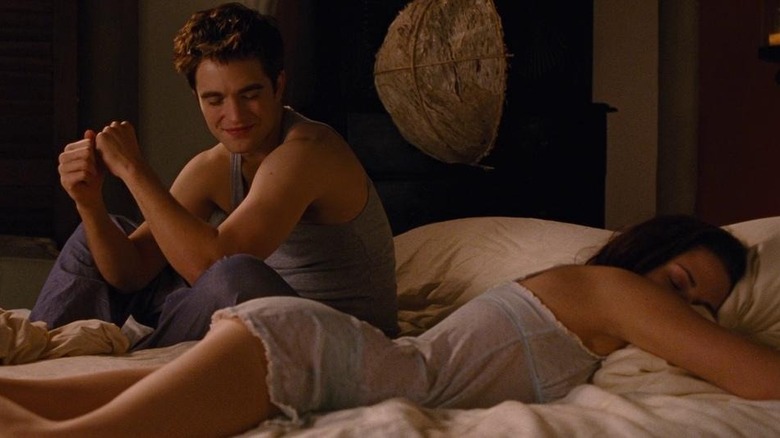 Edward sits in bed with Bella