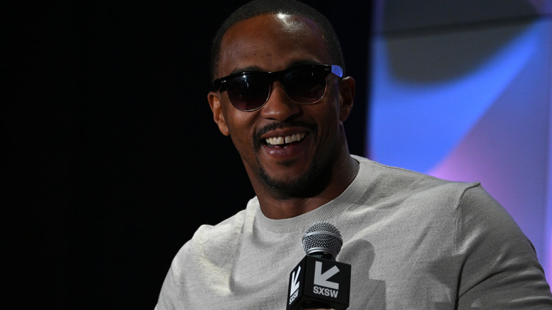 Anthony Mackie wearing sunglasses holding a microphone