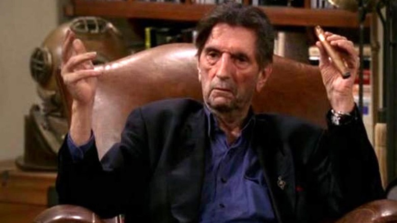 Harry Dean Stanton sits in a recliner with a cigar