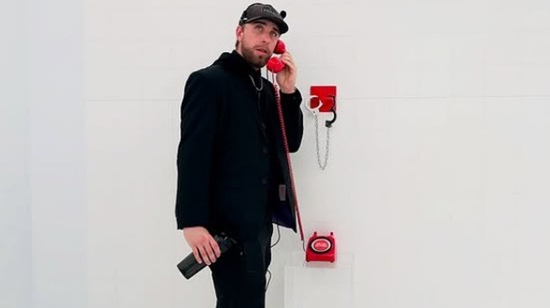 Tyler Conklin holding a red phone in a white room