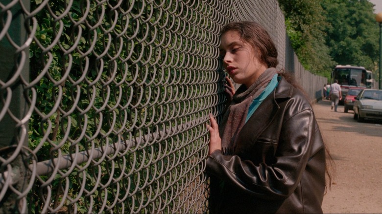 Yanka leans against a fence