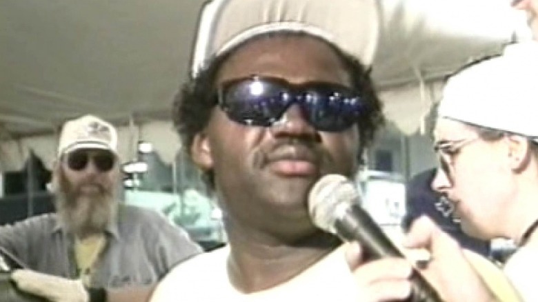 A contestant speaks into microphone in "Hands on a Hardbody" (1997)