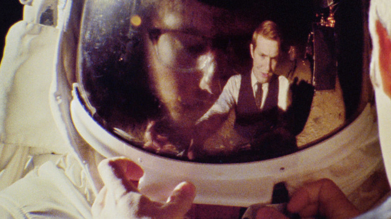 A man is reflected in an astronaut's space helmet