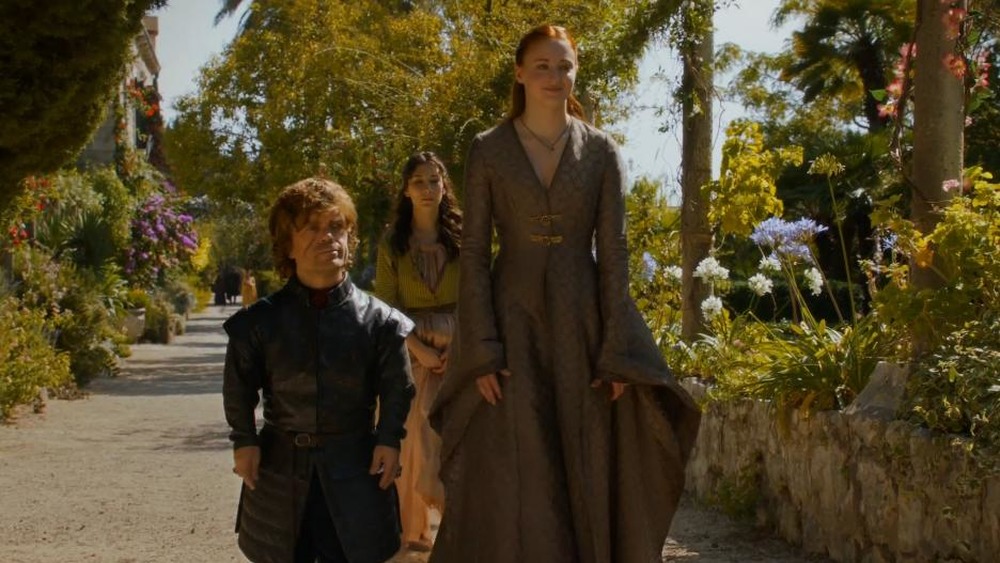 Sophie Turner as Sansa Stark and Peter Dinklage as Tyrion Lannister walking through a garden on Game of Thrones