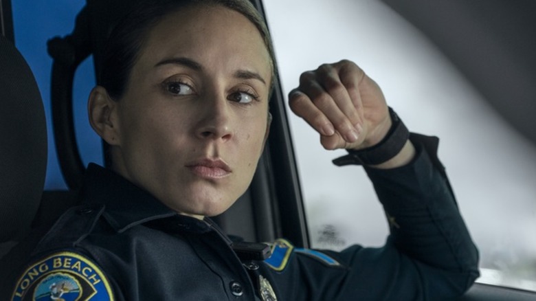 Traci sitting in cop car in uniform