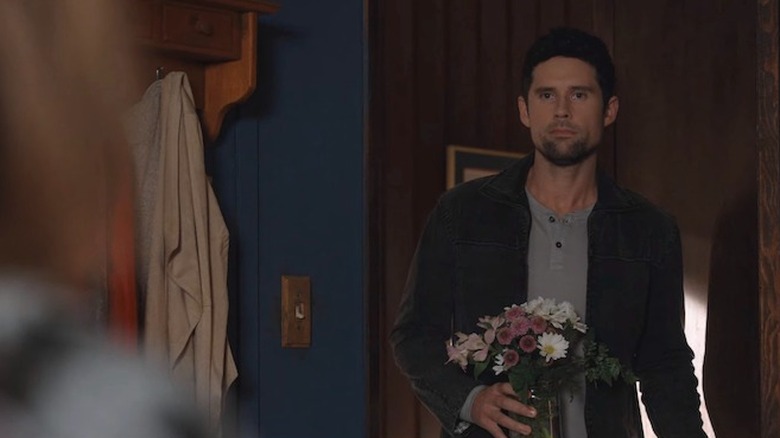 Brady standing in a doorway with a bouquet of flowers