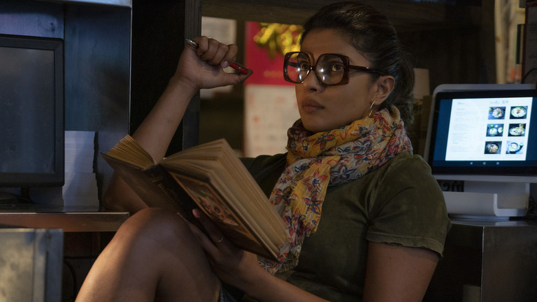 Priyanka Chopra Jones holding a book and wearing glasses in "The Matrix Resurrections"