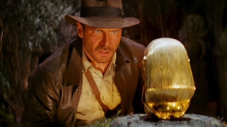 Indiana Jones looking at a gold statue