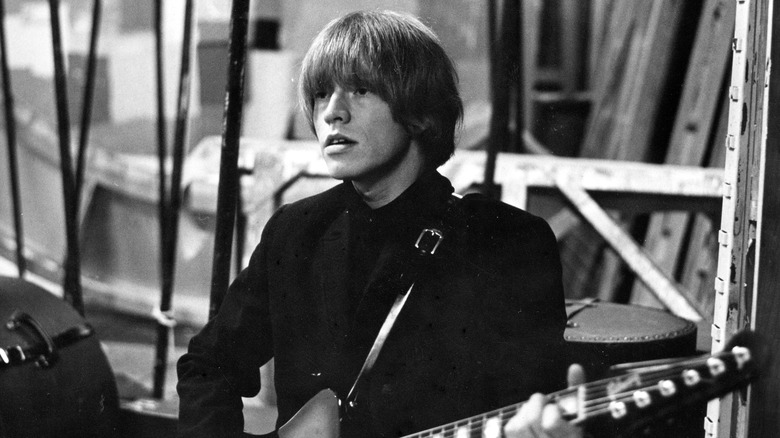 Brian Jones wearing black suit holding guitar