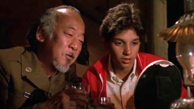 Pat Morita and Ralph Macchio talking in The Karate Kid