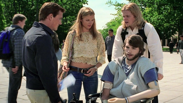 A handicapped Ethan is pushed in a wheelchair by Lenny, who talks to Kayleigh and Tommy in a school square in "The Butterfly Effect" (2004)