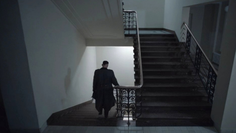 Rudolf Höss walks down dimly lit stairs