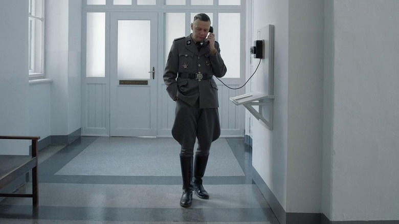 Rudolf Höss talks on a phone in a hallway