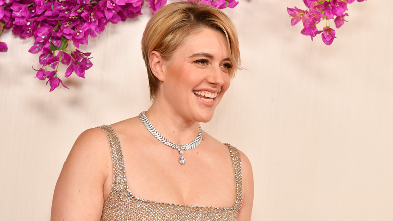 Greta Gerwig laughs gold dress