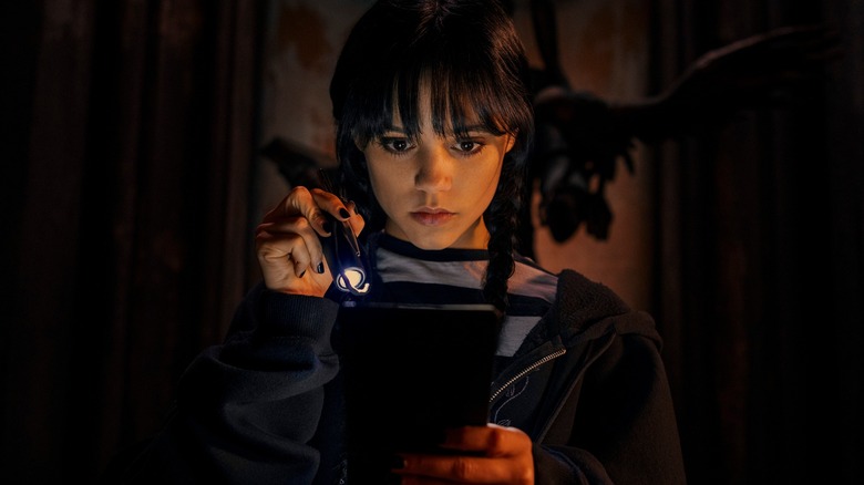 Wednesday Addams holds a flashlight