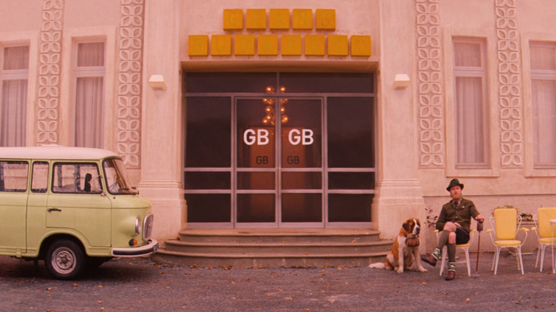 A man and a Saint Bernard in front of the Grand Budapest