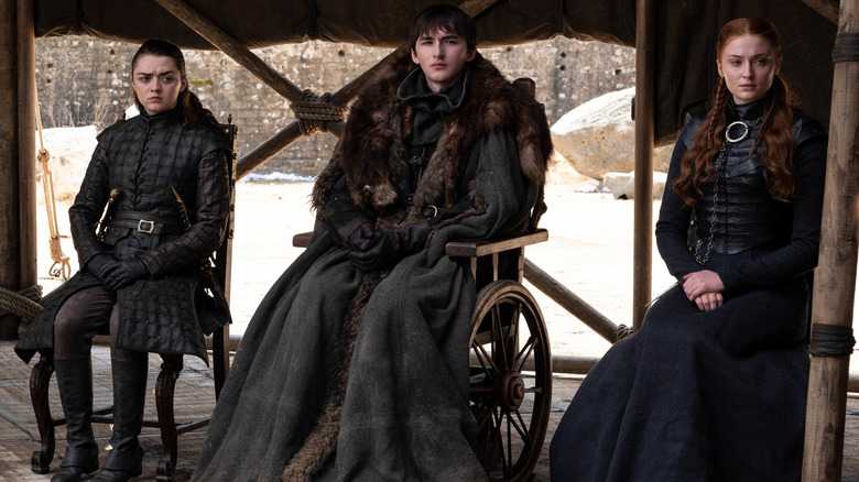 Arya, Bran, and Sansa Stark sitting on chairs