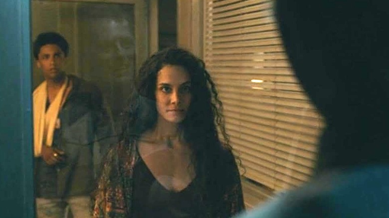 Fatima stares through a glass door at a monster with Ellis standing behind her