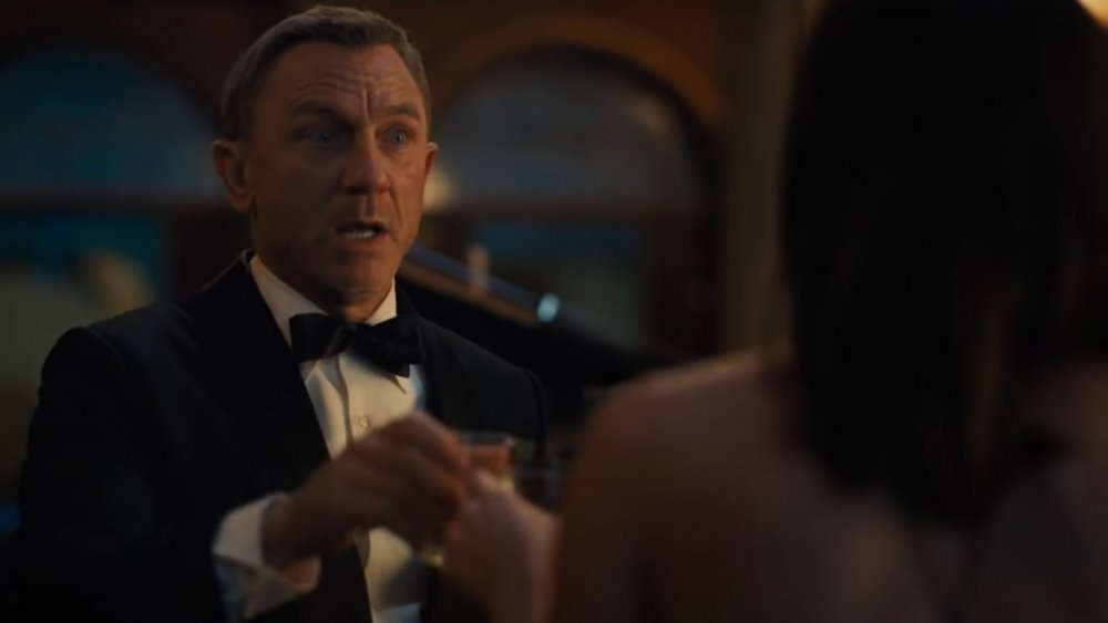 Daniel Craig as James Bond sipping a drink in No Time to Die