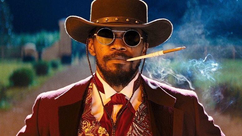 Django dressed as a cowboy and smoking after escaping