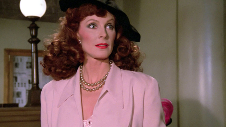 Gates McFadden as Beverly Crusher in black hat and pink dress in The Big Goodbye episode of Star Trek: The Next Generation