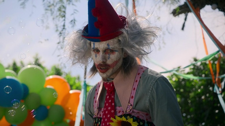 A menacing party clown surrounded by balloons