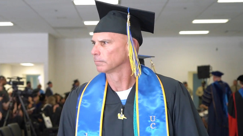 Lyle Menendez wearing graduation regalia from UC Irvine and walking in a graduation ceremony