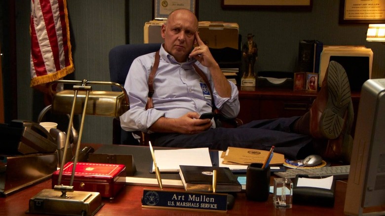 Art sitting in a chair with his feet up on his desk in "Justified."