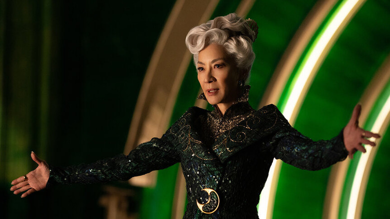 Madam Morrible with her arms spread wide in Wicked