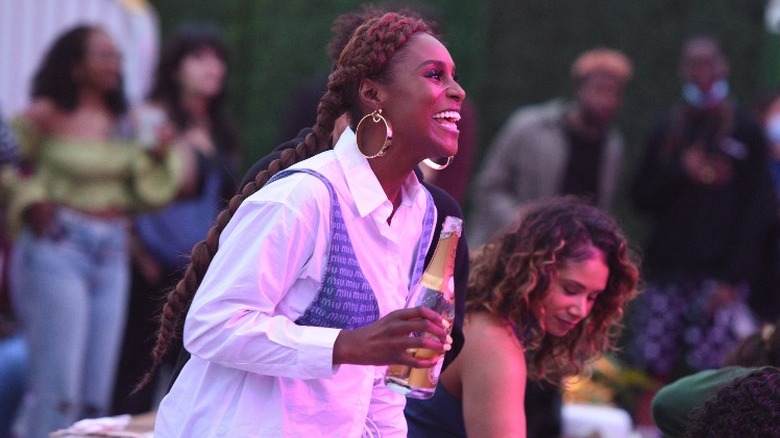 Issa Rae outdoors smiling and holding bottle 