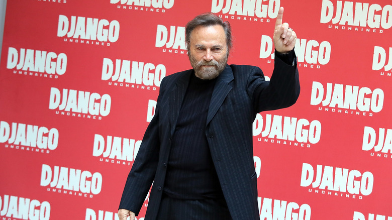 Franco Nero pointing up in front of a Django Unchained display