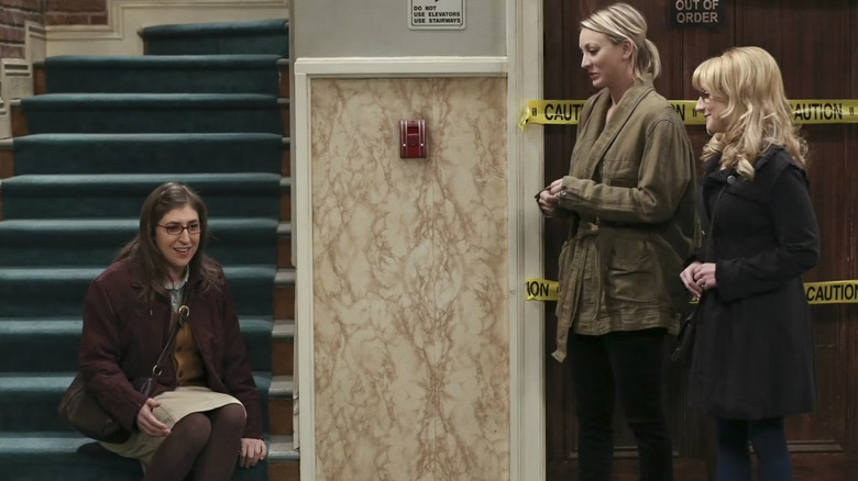 Amy Bernadette and Penny gathered in front of the broken elevator on The Big Bang Theory