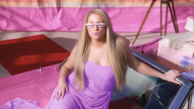 Meghan Trainor wearing a purple dress and sparlkling glasses and lipstick