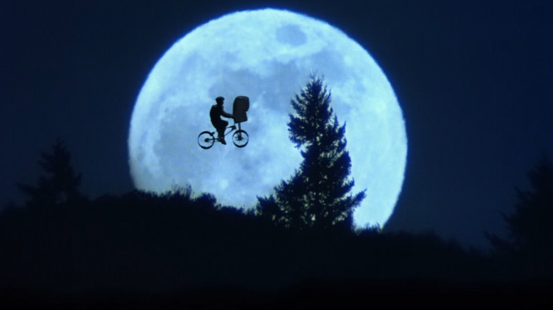 Elliott and E.T. flying in silhouette in front of the moon