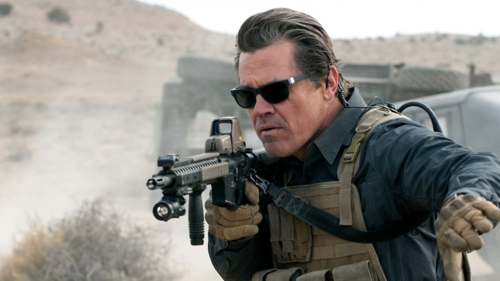 Josh Brolin holding machine gun